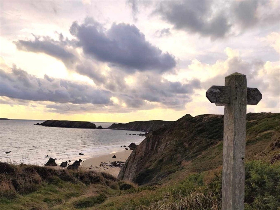View onto Marloes sands and the Pembrokeshire Coast path, with a wooden sign