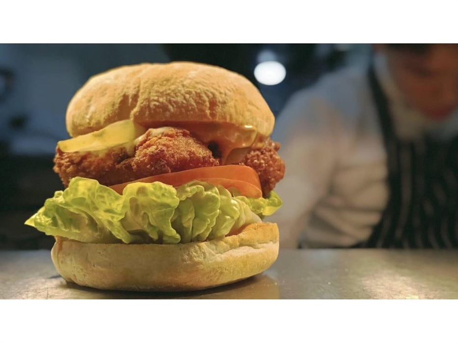 Chicken burger with smoked cheese, burger sauce, gherkins, lettuce, tomatoe, bacon jam with triple cooked chips and slaw