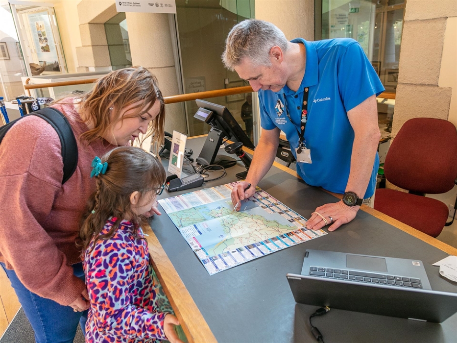 Staff member showing Mother and child Pembrokeshire map at counter to understand the local area.