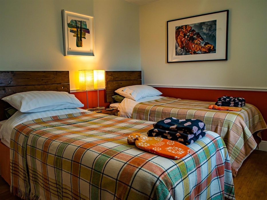 Cwt Mochyn cottage bedroom with twin single beds with Welsh blankets and hot water bottles