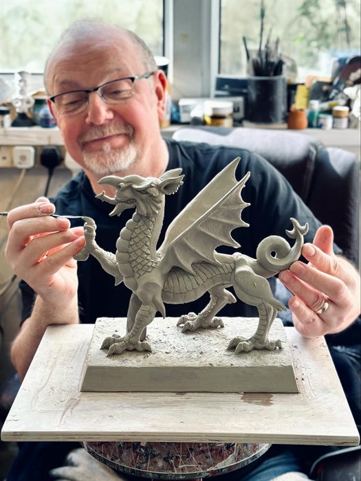 The photo depicts Richard in his studio at the shop, sculpting an impressive dragon.