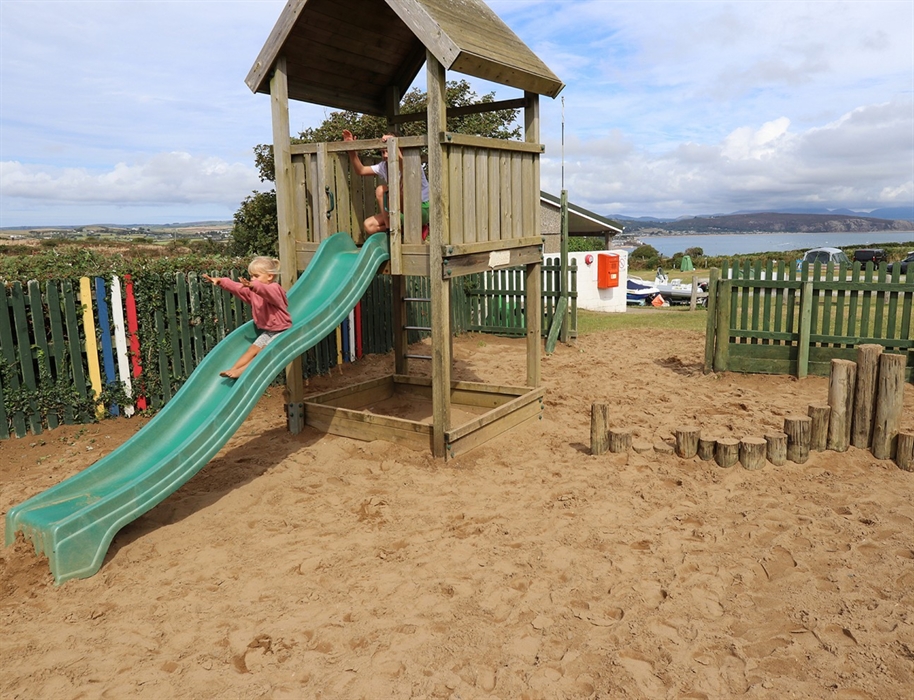 Children playing in sandy play area with sea view
