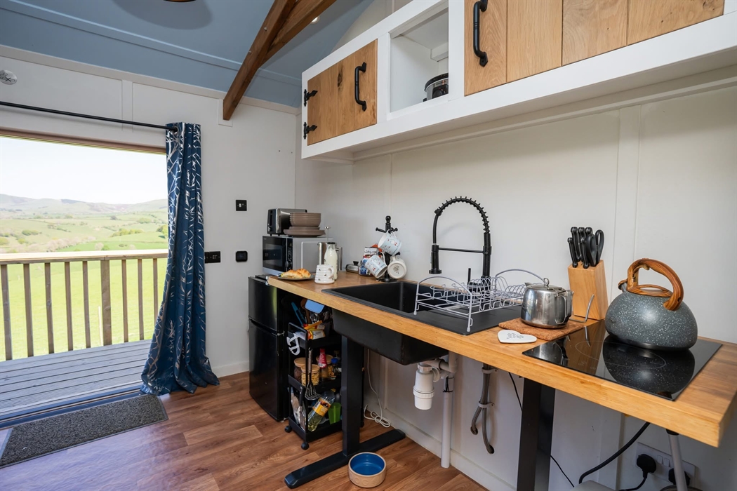 Standing next to the recliner chairs (back against the side) looking at the kitchen. There is an adjustable worktop which rises to 90cm and falls to 7