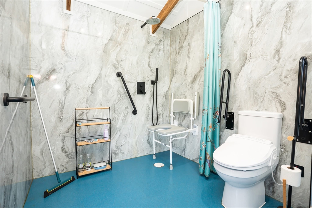 Photo of the wetroom: fold down shower chair with legs. Arms can be folded up whilst transferring from a wheelchair or kept down if going from standin