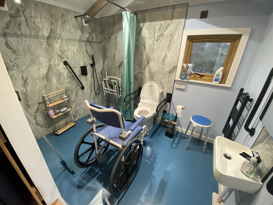 Shower commode wheelchair infront of the toilet to give an idea of scale in the wetroom. Also lowered sink is to the right on the toilet when looking