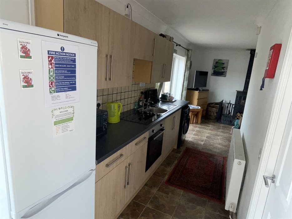Shows fridge freezer, kitchen wall and base cabinets, ceramic hob, single electric oven, sink, washing machine, radiator and French doors.