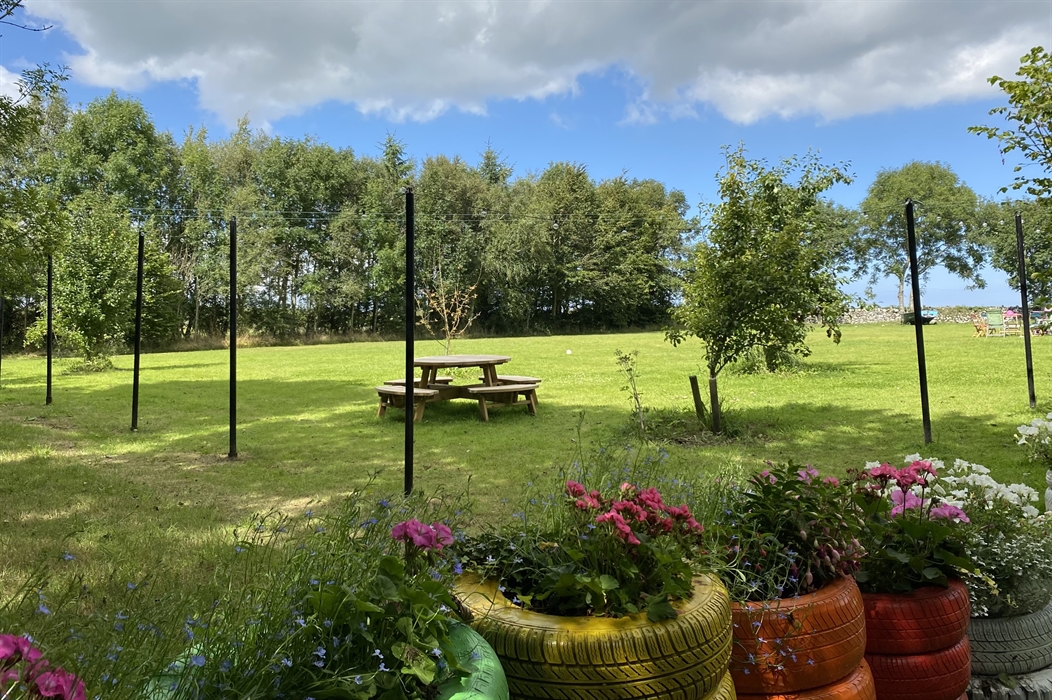 Green lawn for play and event space with colourful tiers, flower and picnic tables