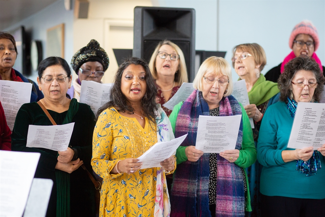 A group of women singing with song sheets.