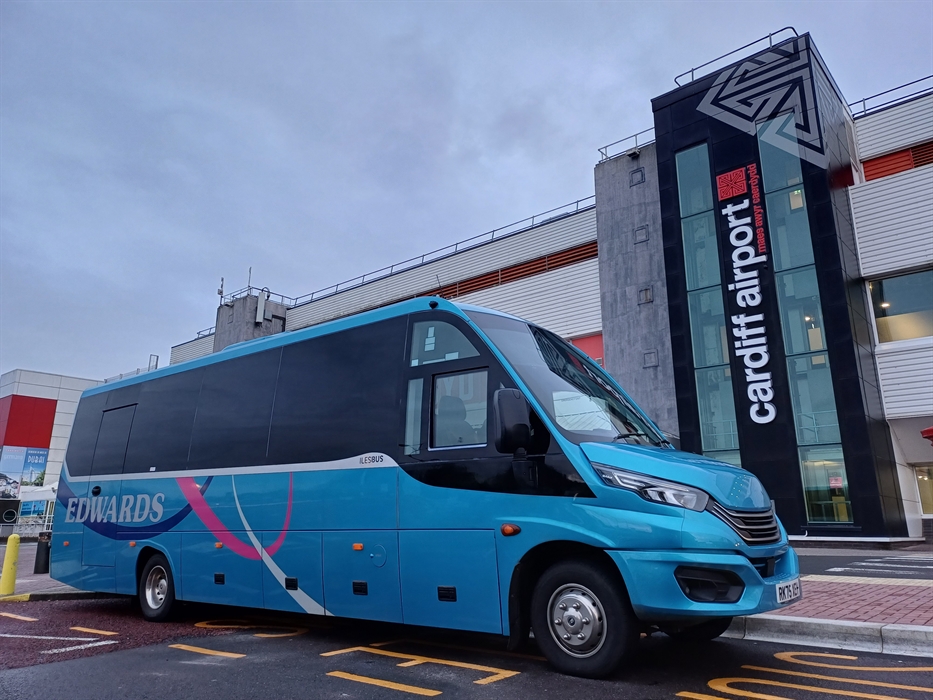 A blue mini bus parked outside an airport