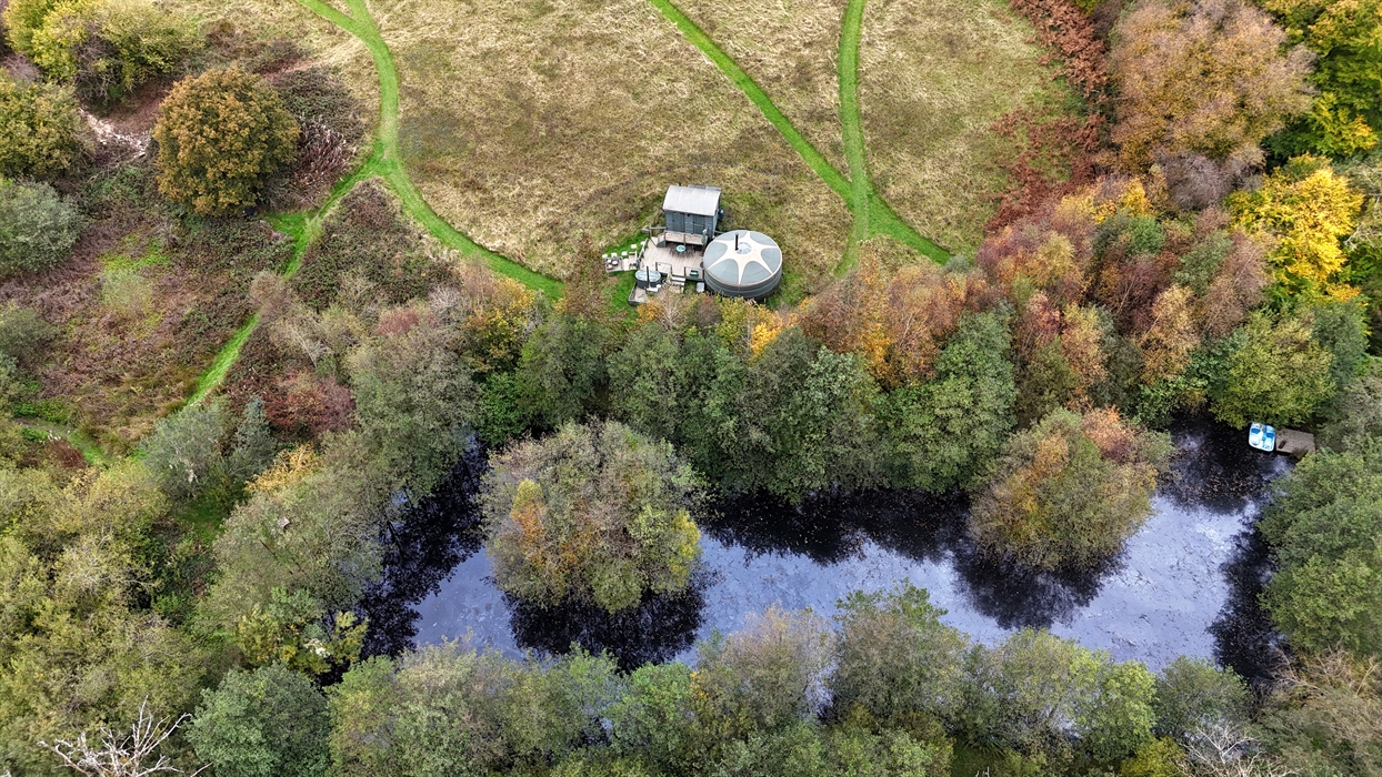 The yurt is situated at the bottom of the meadow, behind a small lake fringed with trees.