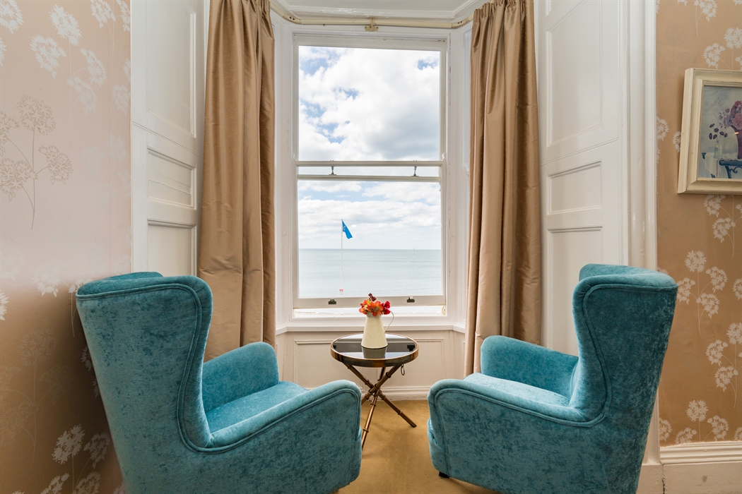 Hotel room with two chairs and table by the window with a sea view