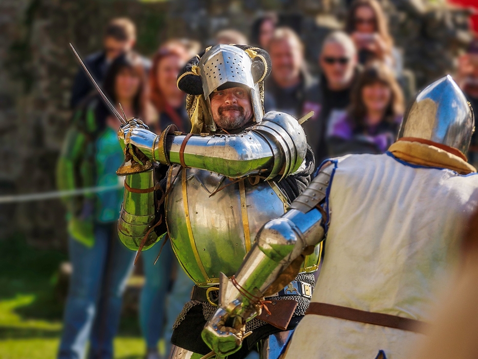 Two re-enactors dressed in knights clothing in front of crowd at an event