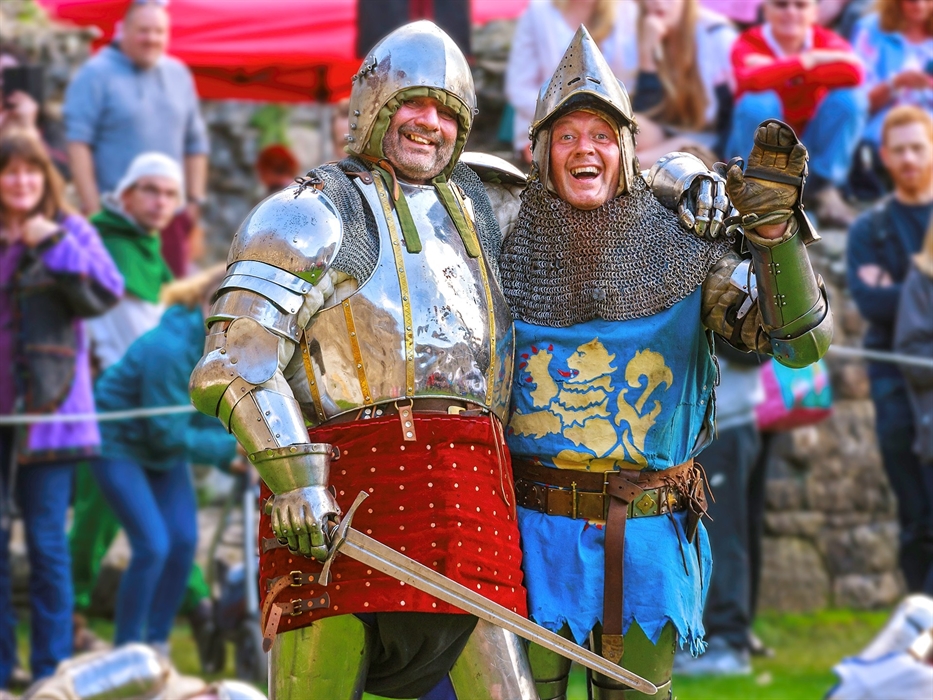 Two re-enactors dressed in knights clothing standing in front of crowd.