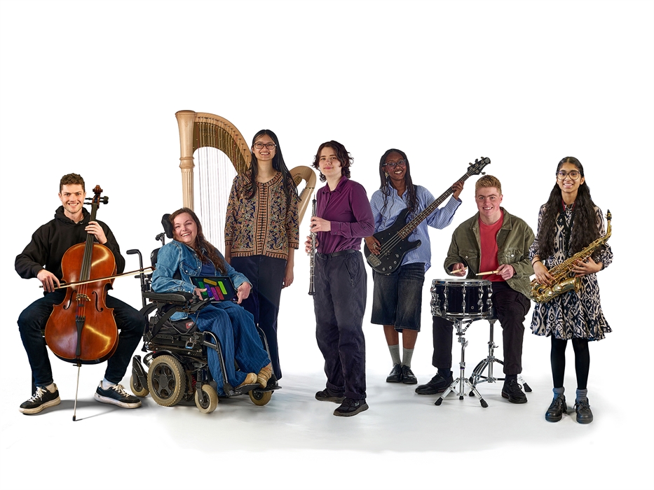 Members of the National Open Youth Orchestra pose in front of a white background with their instruments. One member of the group is a wheelchair user.