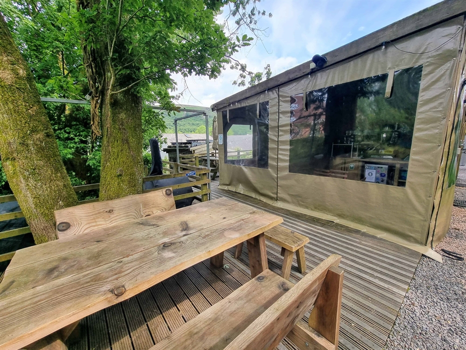 a picnic table sat under a tree next to a wooden building
