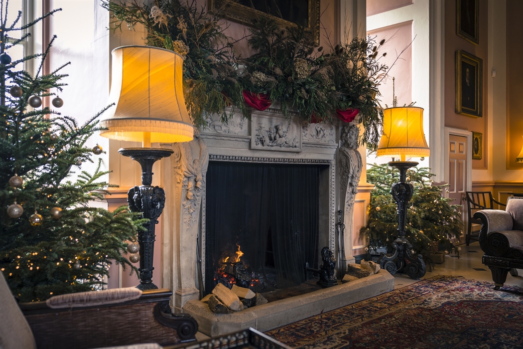 Main Hall lit fireplace with christmas trees and festive decorations.