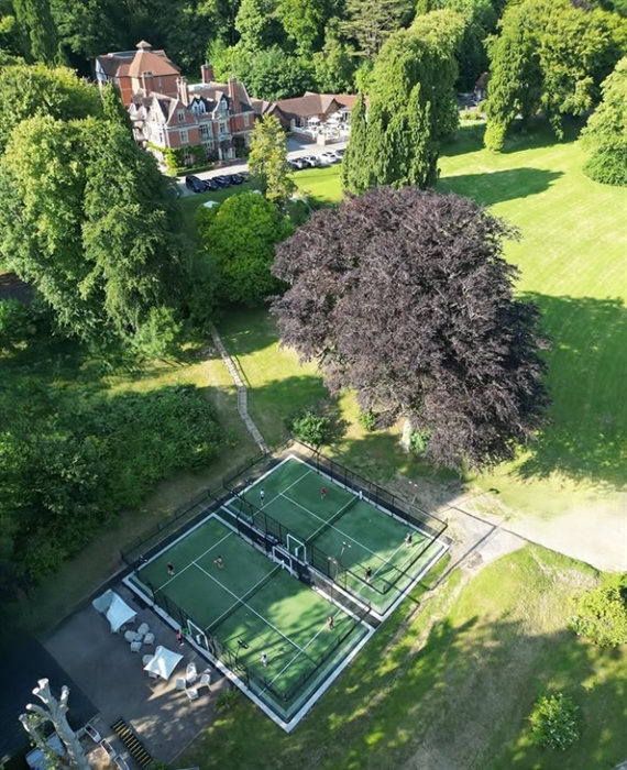 Aerial shot of tennis courts and a hotel surrounded by trees