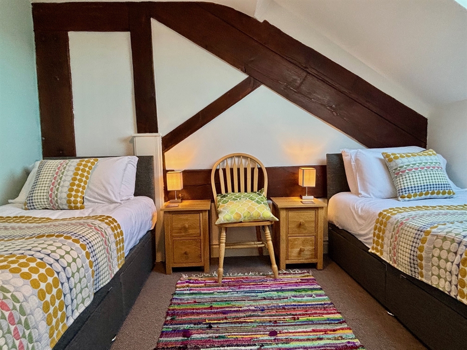 Two single beds with colourful throws in bedroom, Wales holiday cottage