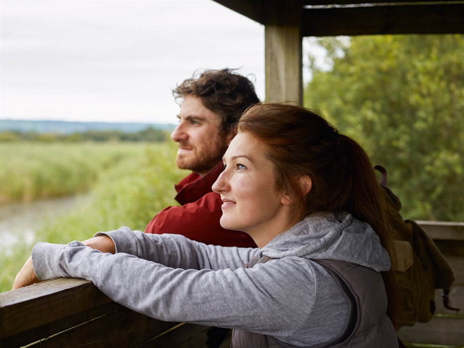 Visitors looking out at wetlands from a hide at WWT Llanelli