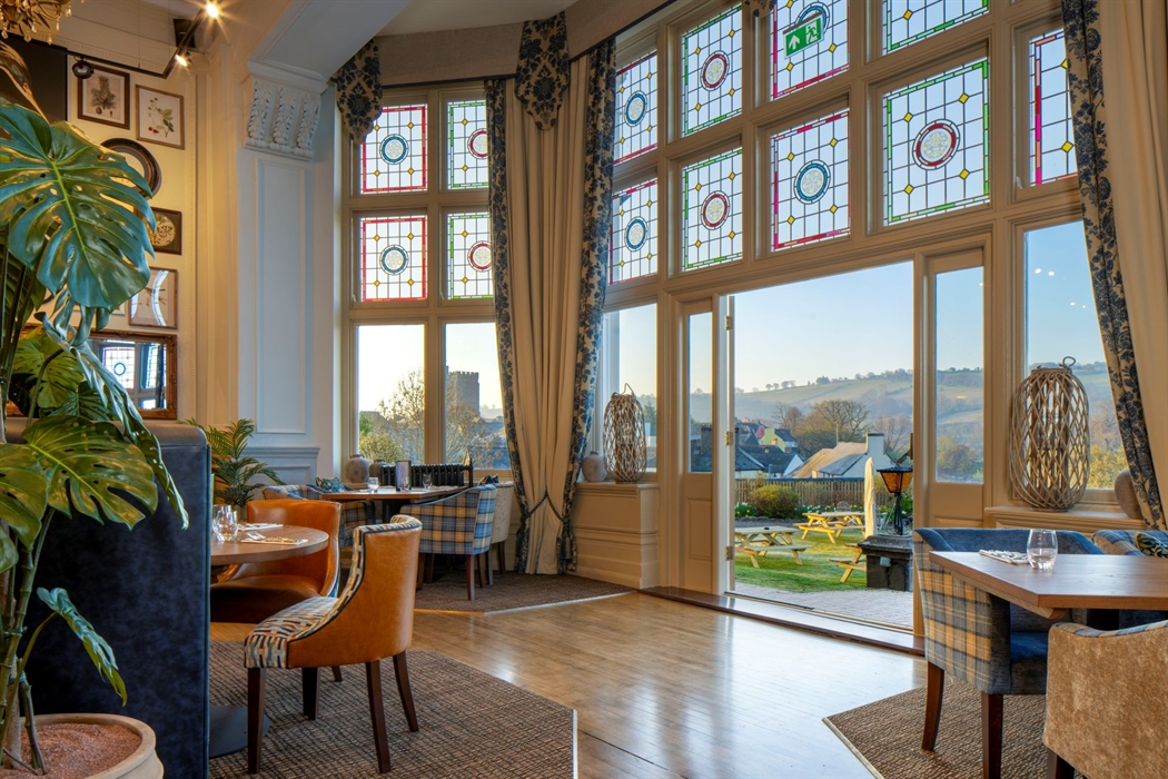 Tables in a restaurant with large doors leading out toward views of the countryside