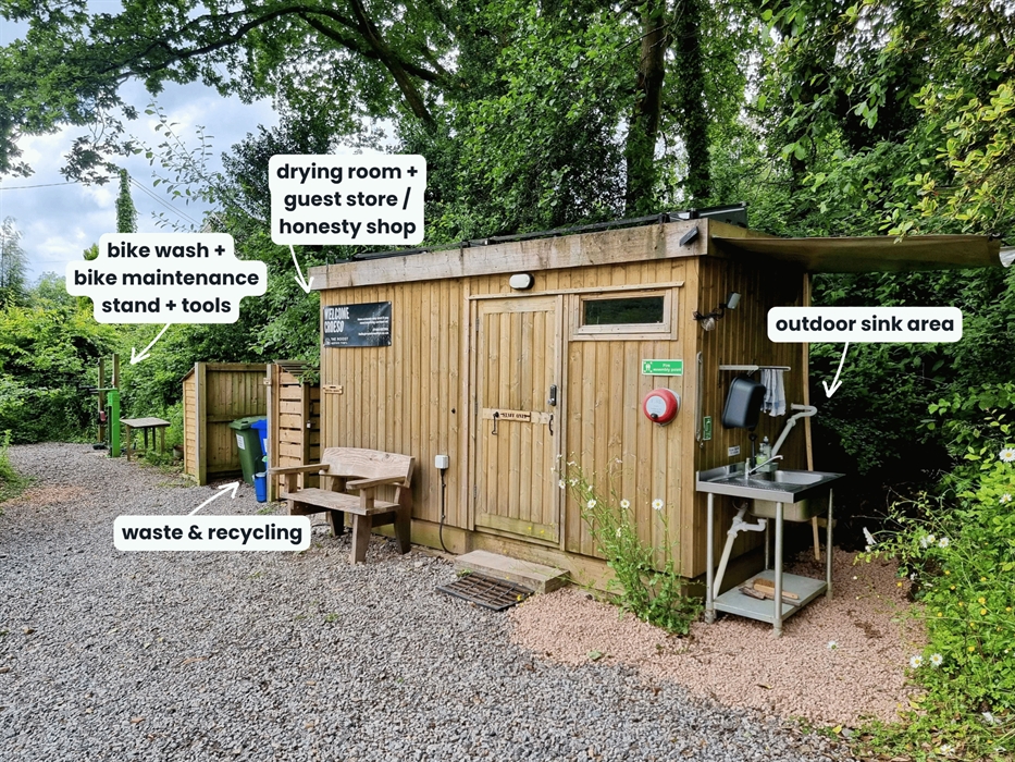 A wooden cabin in the trees with sink and facilities with name labels