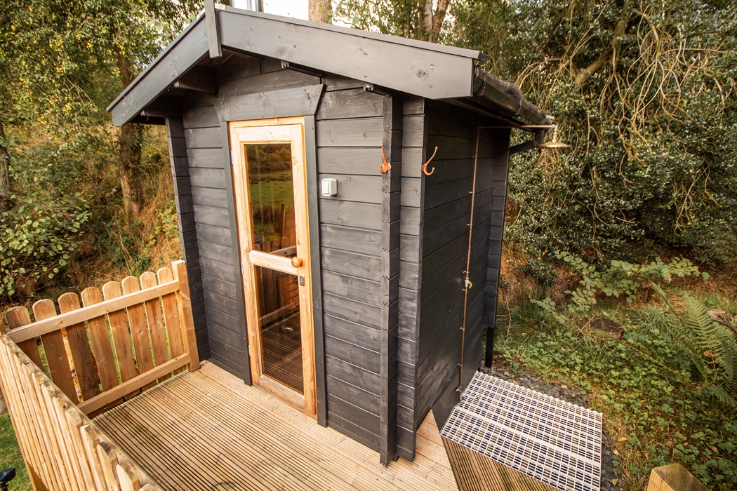 Private wood fired sauna area with robes and an outdoor cold water shower.
