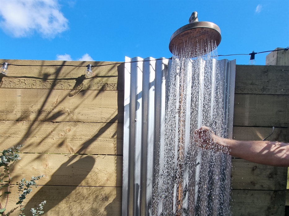 An outdoor shower raining down water against a blue sky