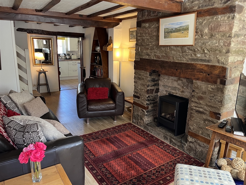 Chancery cottage sitting room with electric wood burner, comfortable leather sofa and armchair.