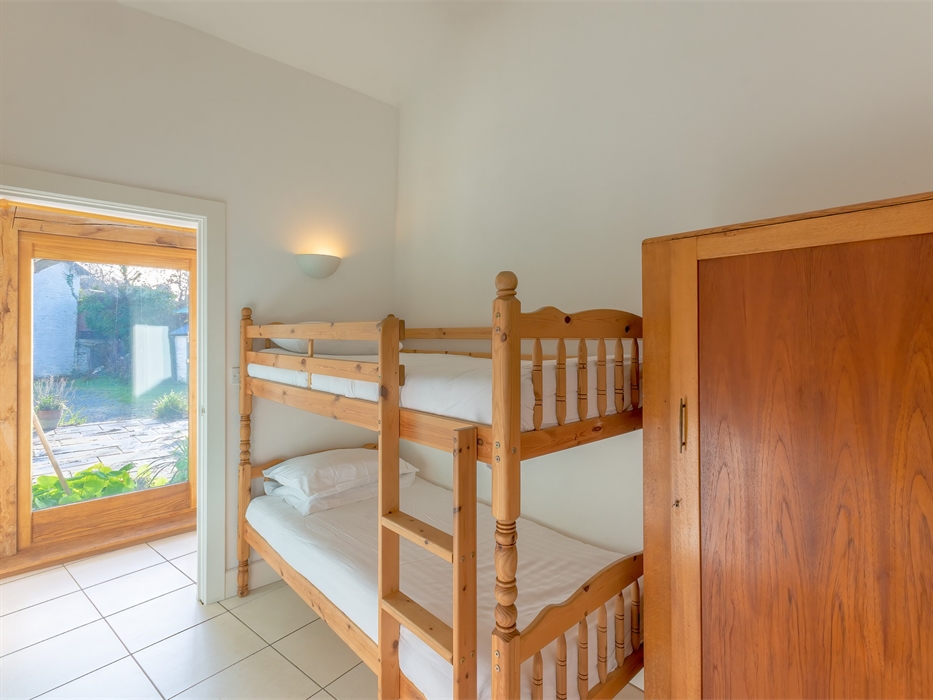 Bunk beds with wardrobe, and view to outside area from corridor beyond bedroom door