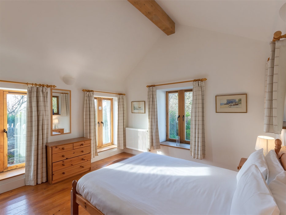 Double bed with three windows and a chest of drawers