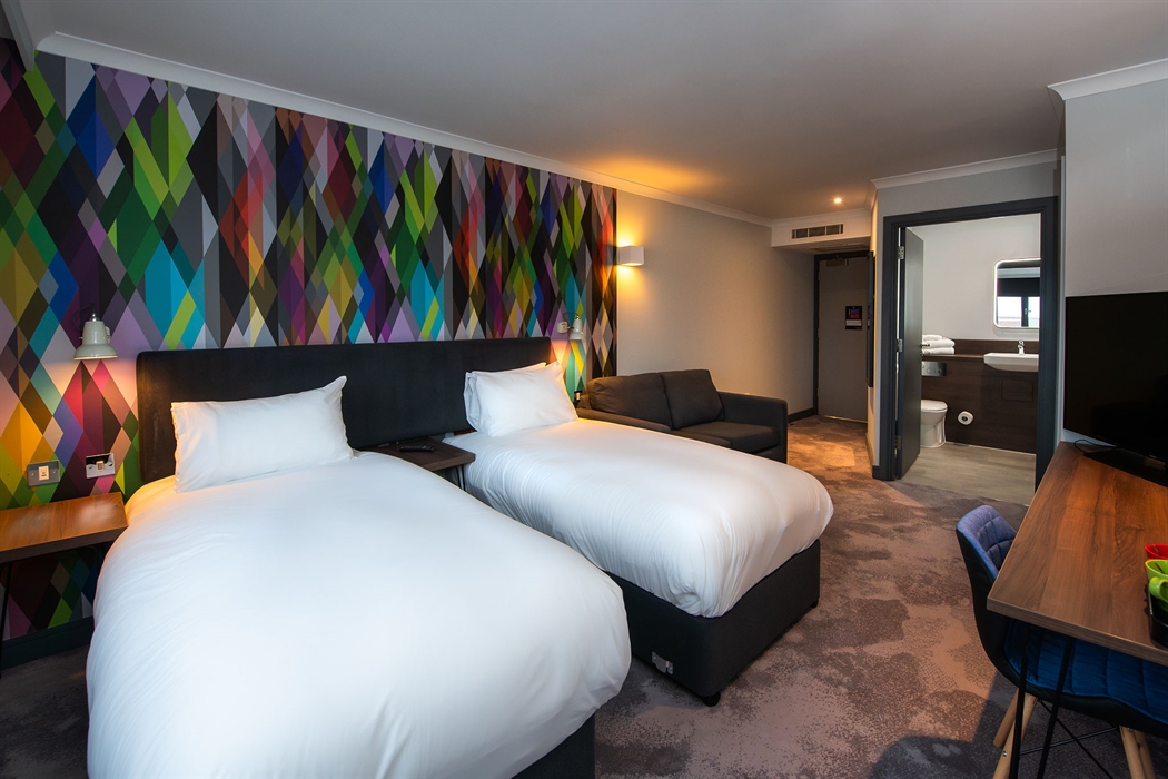 Twin beds, desk and chair, TV and door to en-suite shower room.