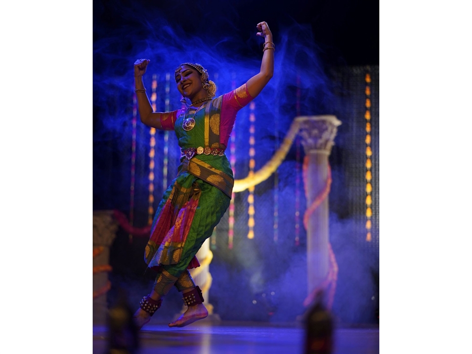 A female dancer, dances on a stage dressed in an indian Bharatanatyam costume (pleated saree).