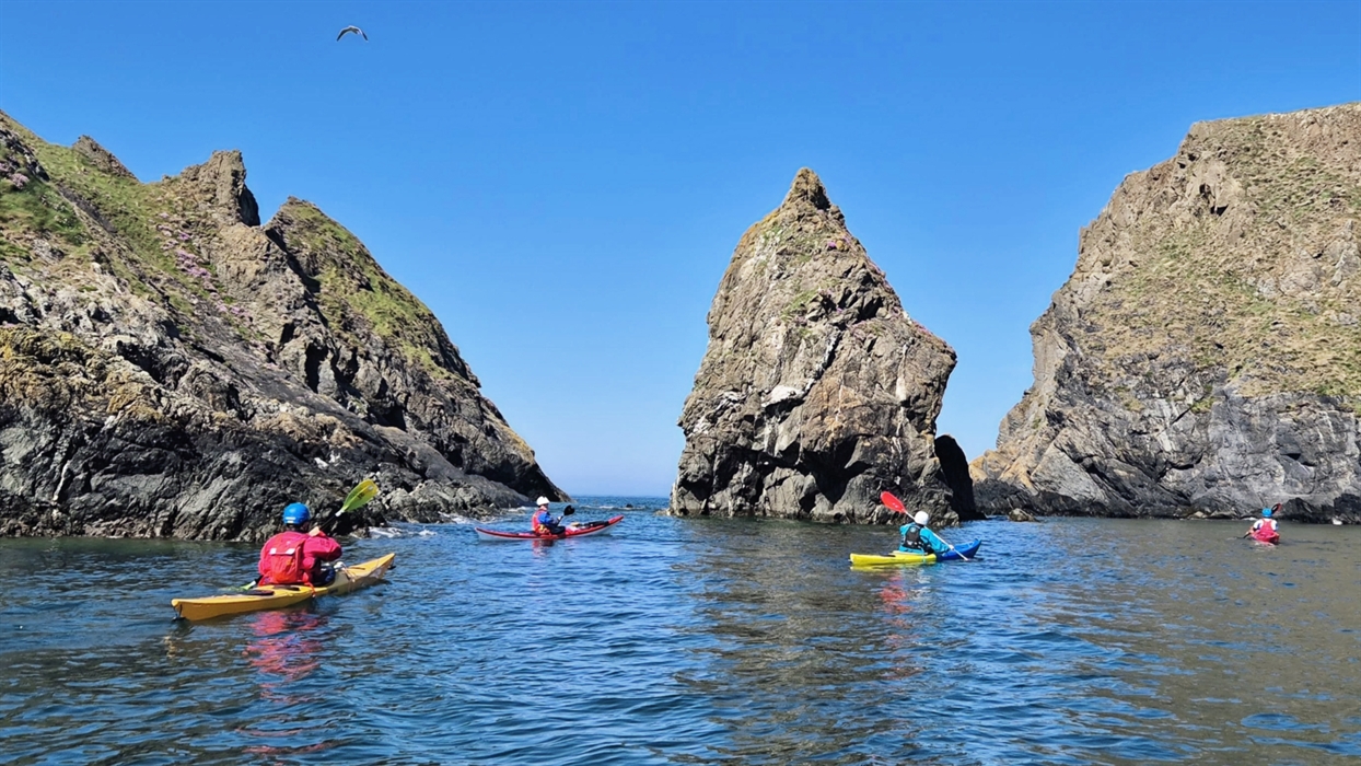 Kayakers paddling around large rock formations