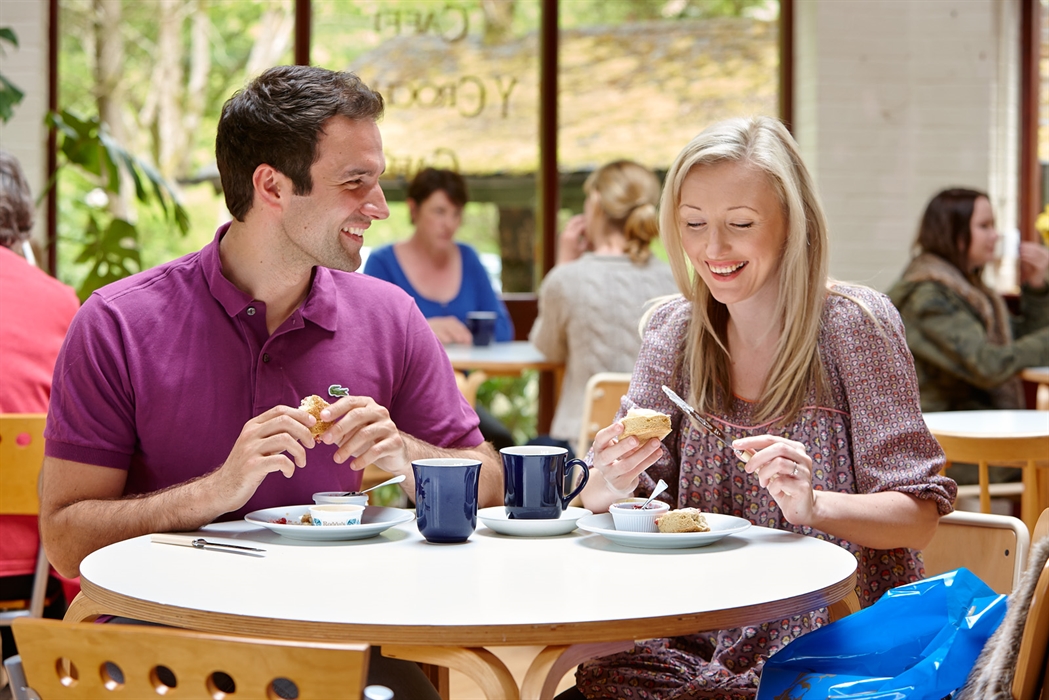 A couple eating scones and drinking tea.