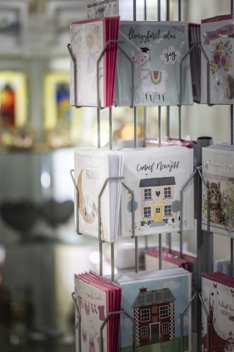 Display stand of colourful Welsh-language greeting cards and local gift cards inside the tourist information shop.