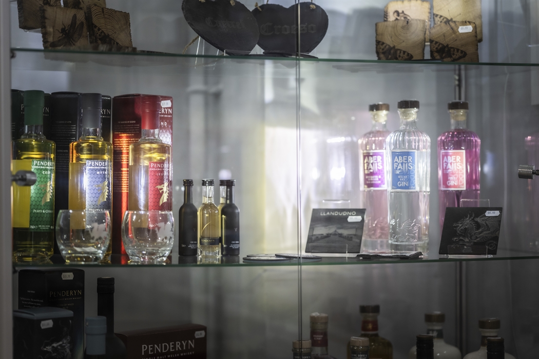Glass display cabinet featuring Welsh spirits, Penderyn whisky, local gin and artisan gifts from North Wales producers.