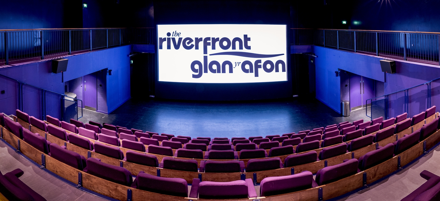 An empty cinema space with a projector with the theatre logo.