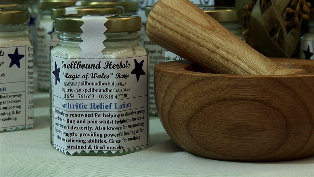A jar of arthritic relief lotion beside a wooden pestle and mortar