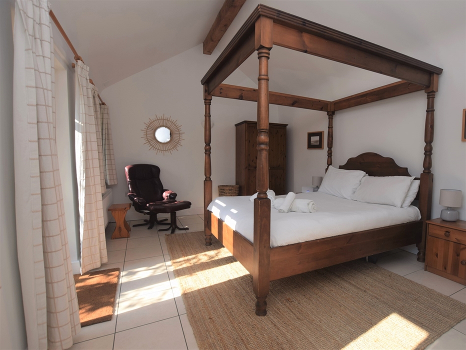 Bedroom with four poster bed and chair