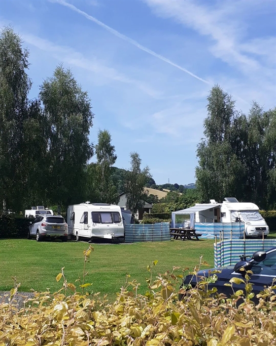 Pont kemys caravan park, hardstanding pitches for caravans and campervans surrounded by hedges and blue sky