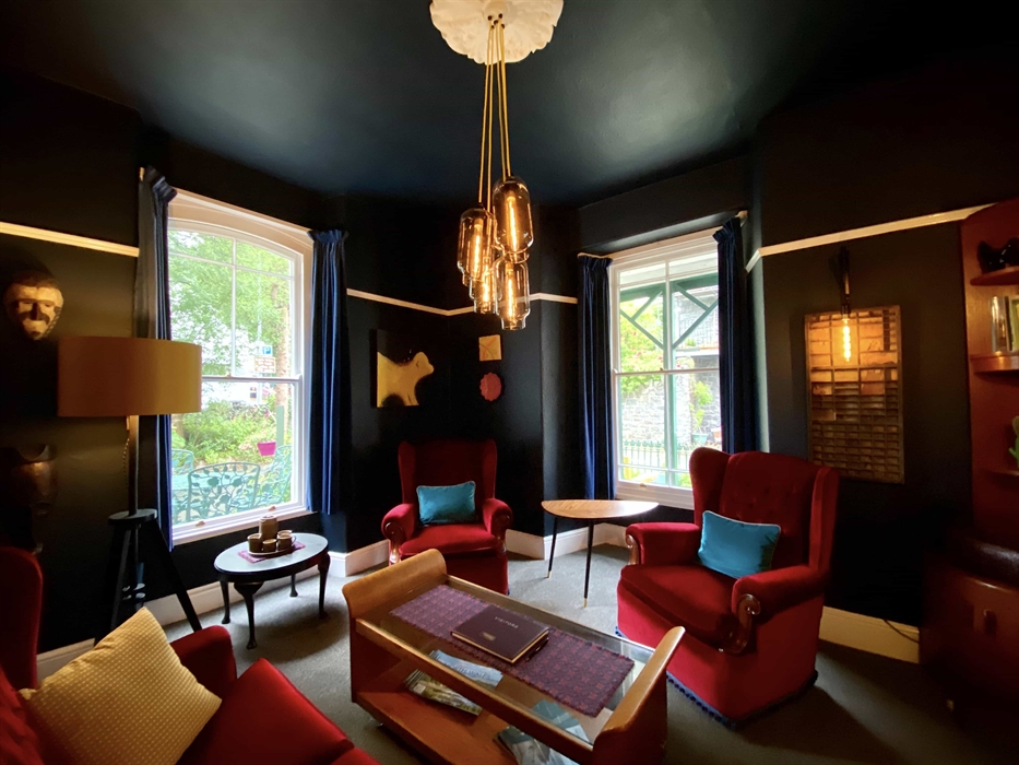 grey sofa against a black wall with yellow and red cushions, and mirrors above it