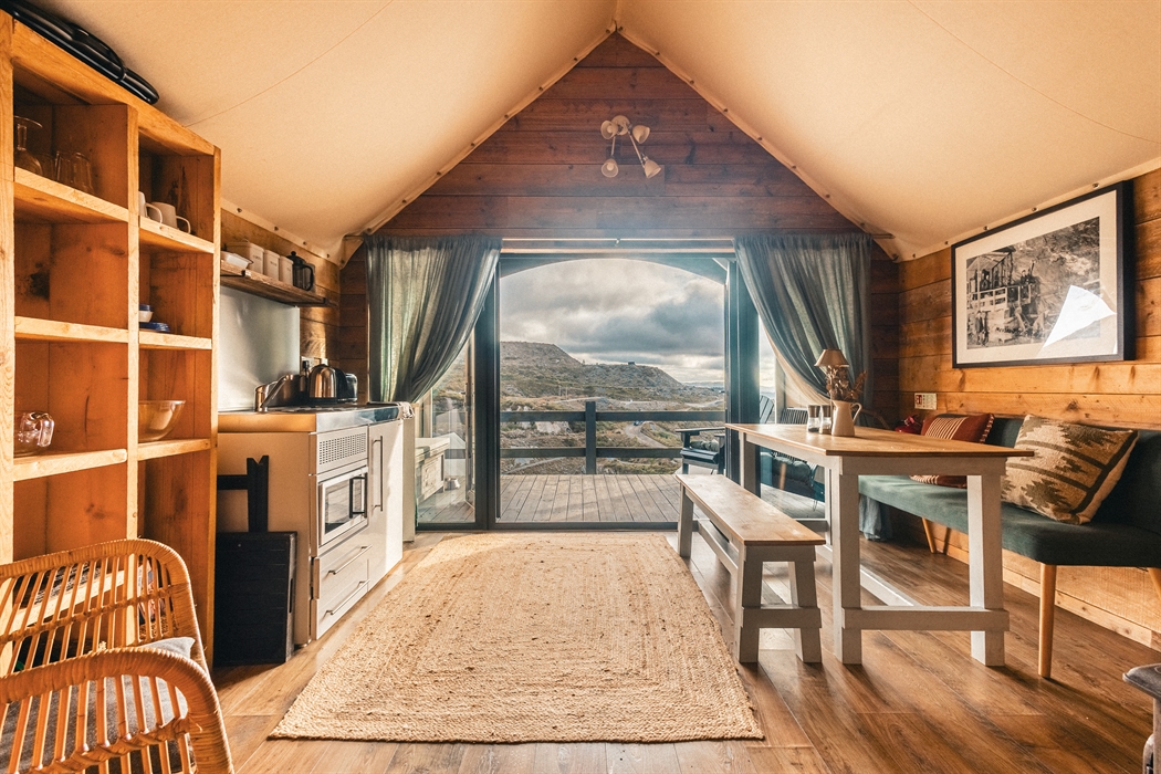 Interior of llechwedd glamping tent showing kitchenette, dining table and views of the moutnains outsite