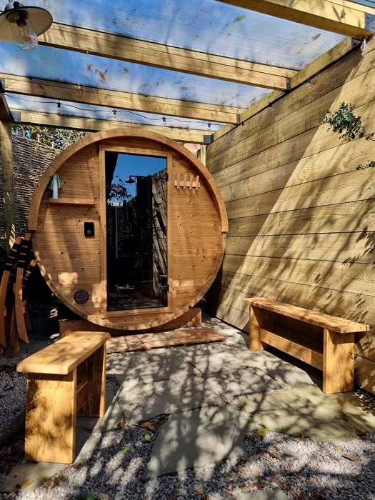 A round wooden barrel sauna with a glass door and benches for sitting on